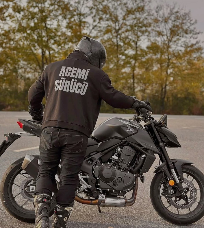 Acemi Sürücü reflektörlü siyah hoodie giyen sürücü motosikletin yanında
