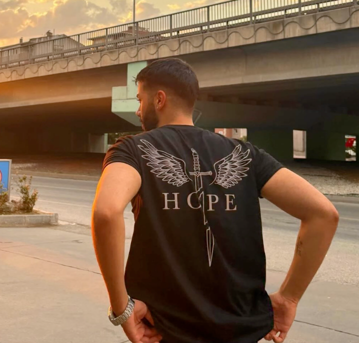 Hope kanatlı kılıç baskılı siyah tişört giyen model, arkadan görünüm