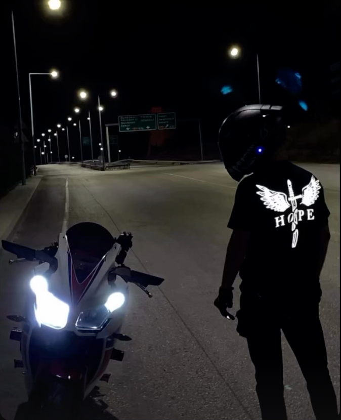 Gece yolda motosiklet farı önünde Hope reflektör baskısı parlayan sürücü