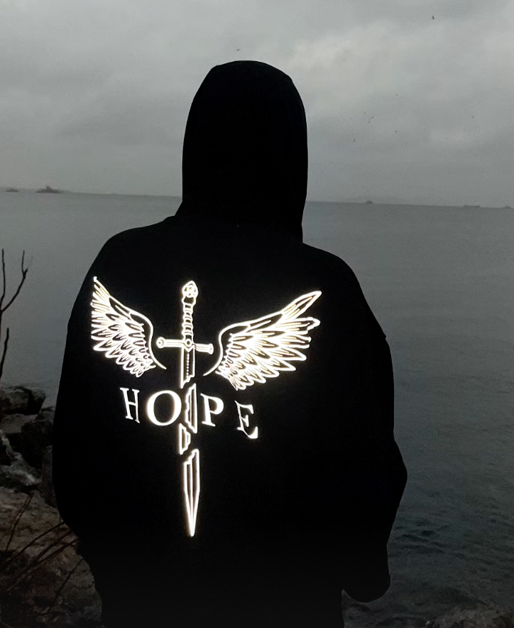 Deniz kenarında karanlıkta parlayan Hope reflektörlü hoodie, arkadan görünüm